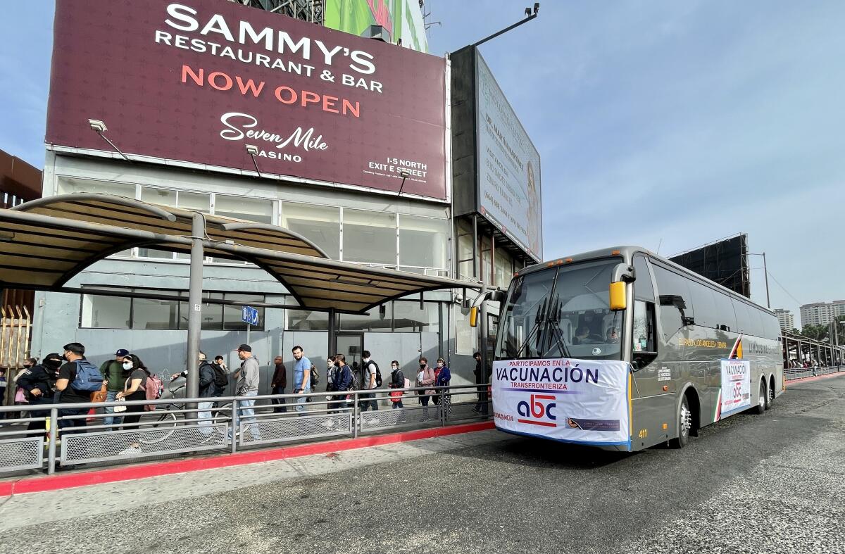 A bus with a banner reading "Vacunacion" waits at the San Ysidro border crossing.