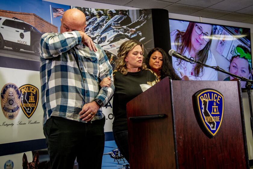 RIVERSIDE, CA - NOVEMBER 30, 2022: Michelle Blandin, middle, grasps her husbands arm while talking about her slain sister and parents at the home where she grew up at a press conference at the Riverside Police Department's Magnolia Station on November 30, 2022 in Riverside, California. The victims were identified as Mark Winek, 69; his wife, Sharie Winek, 65; and their daughter Brooke Winek, 38, who lived in the house with Brooke's two teenage daughters. The 15-year-old teen was involved in an online relationship with a predator who is accused of the murders. Police say Austin Lee Edwards, 28, of North Chesterfield, Va., killed the three before leaving with the teen in his vehicle. He was later killed in a shoot-out with police in San Bernardino County.The teen is safe.(Gina Ferazzi / Los Angeles Times)