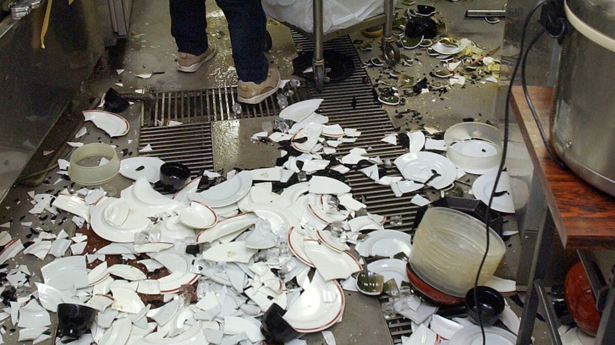 Workers clean up broken dishes at a restaurant in Kushiro, on the northern Japanese island of Hokkaido, after a powerful earthquake on Nov. 29, 2004. (Kotaro Ebara / Asahi Shimbun)