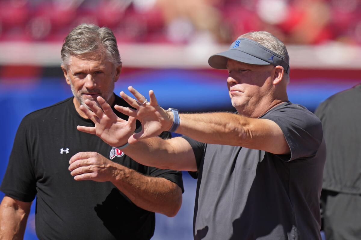 Utah head coach Kyle Whittingham, left, and UCLA head coach Chip Kelly talk before Saturday's game.