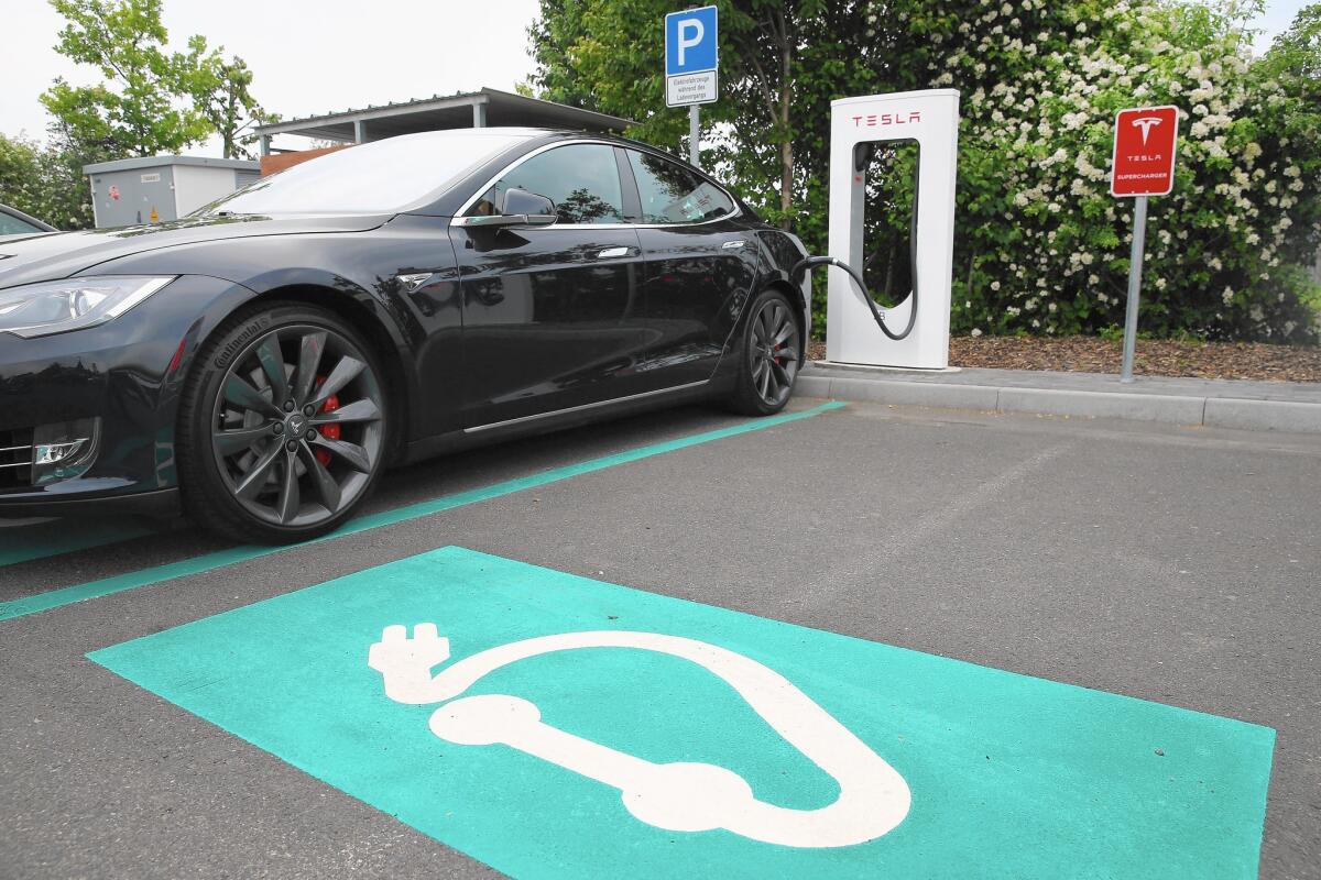 A Tesla executive said the company’s goal is to create a mass market for electric vehicles, “where 100% of the transportation in the U.S. and the world is electric.” Above, a sedan is charged in Germany.