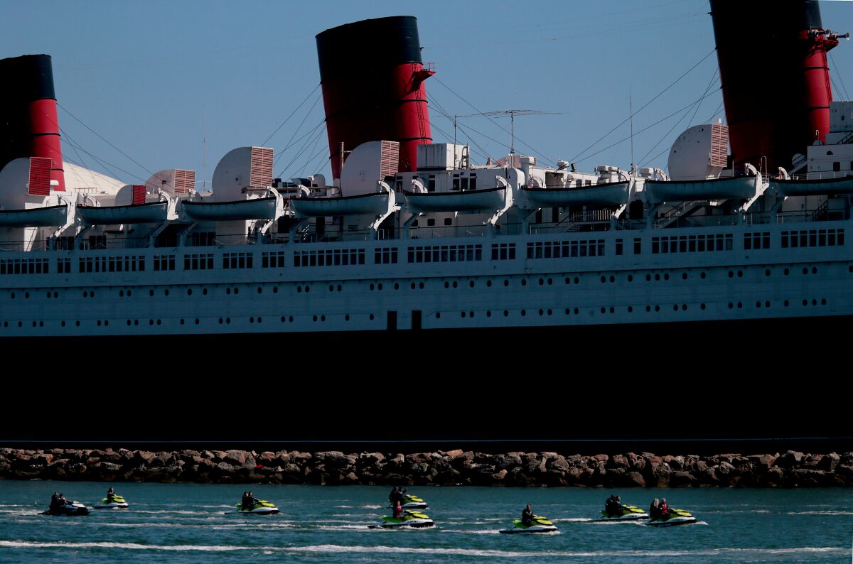 A flotilla of personal water craft motor past the Queen Mary in Long Beach. 