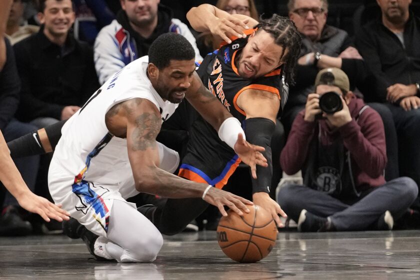 Brooklyn Nets guard Kyrie Irving, left, and New York Knicks guard Jalen Brunson fight for a loose ball during the first half of an NBA basketball game, Saturday, Jan. 28, 2023, in New York. (AP Photo/Mary Altaffer)