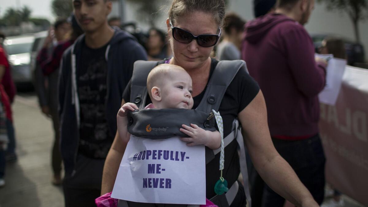 A woman participates with her infant daughter in the MeToo Survivors' March in Los Angeles on Nov. 12, 2017.