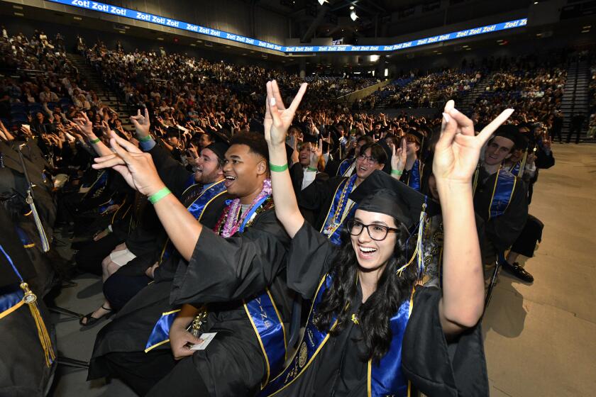 Grads Kaneen Muldrow and Adilene Masopust give the 'zot' cheer at the conclusion of the commencement ceremony for the schools of Education and Physical Sciences at UC Irvine.