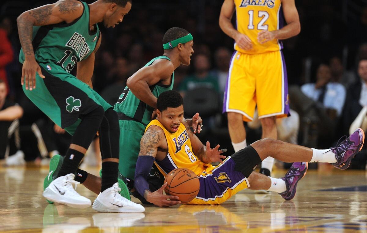 Lakers guard Kent Bazemore tries to collect a loose ball against Celtics point guard Rajon Rondo.