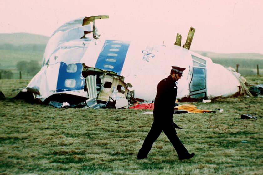 An officer walks past the wreckage of Pan Am flight 103 near Lockerbie, Scotland, in 1988.