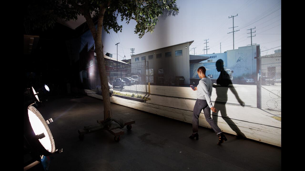 Actress Issa Rae passes by a background photo of a Los Angeles street scene.