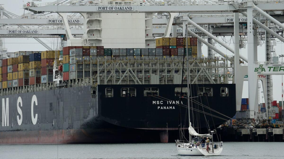 A sailboat makes its way past the container ship MSC Ivana as it is unloaded at the Port of Oakland in March.