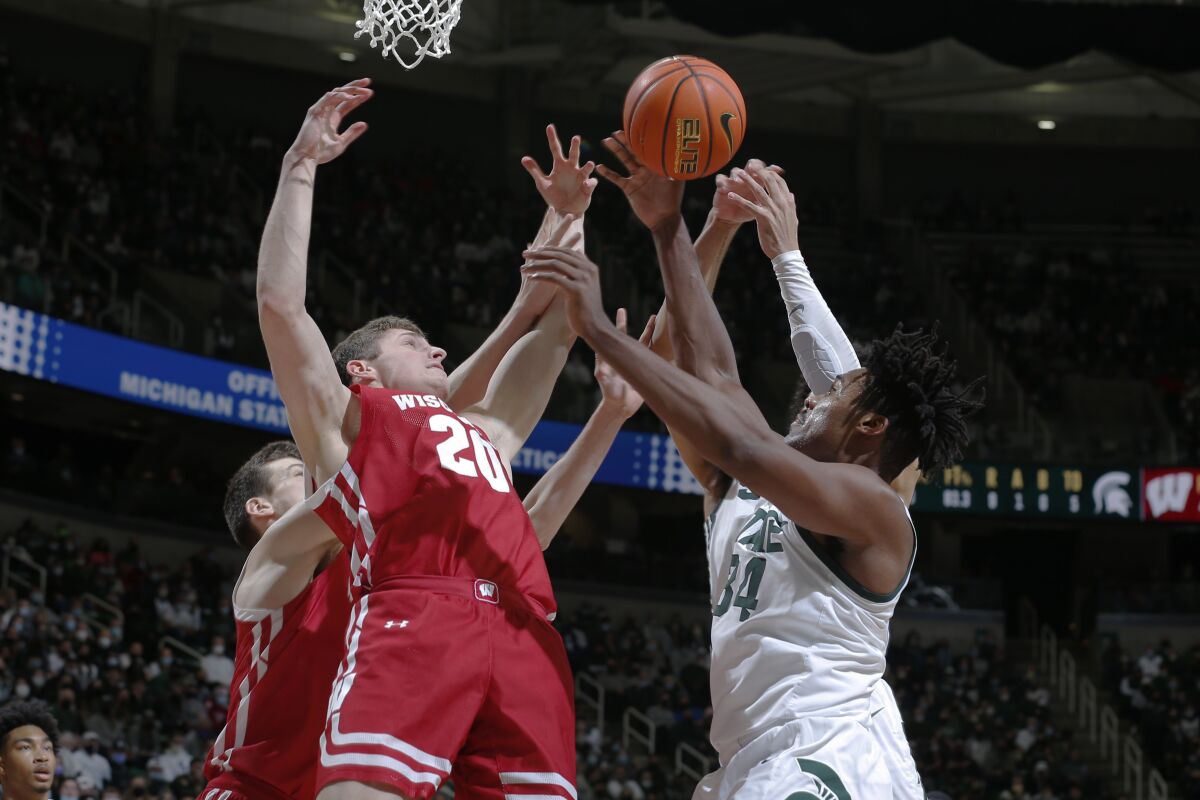 Michigan State's Julius Marble, right, and Wisconsin's Ben Carlson (20) reach for a rebound during the first half of an NCAA college basketball game, Tuesday, Feb. 8, 2022, in East Lansing, Mich. (AP Photo/Al Goldis)