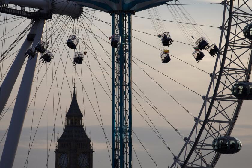 People ride on a fairground ride with the London Eye and Big Ben as a backdrop as the sun sets in London in September 2013.
