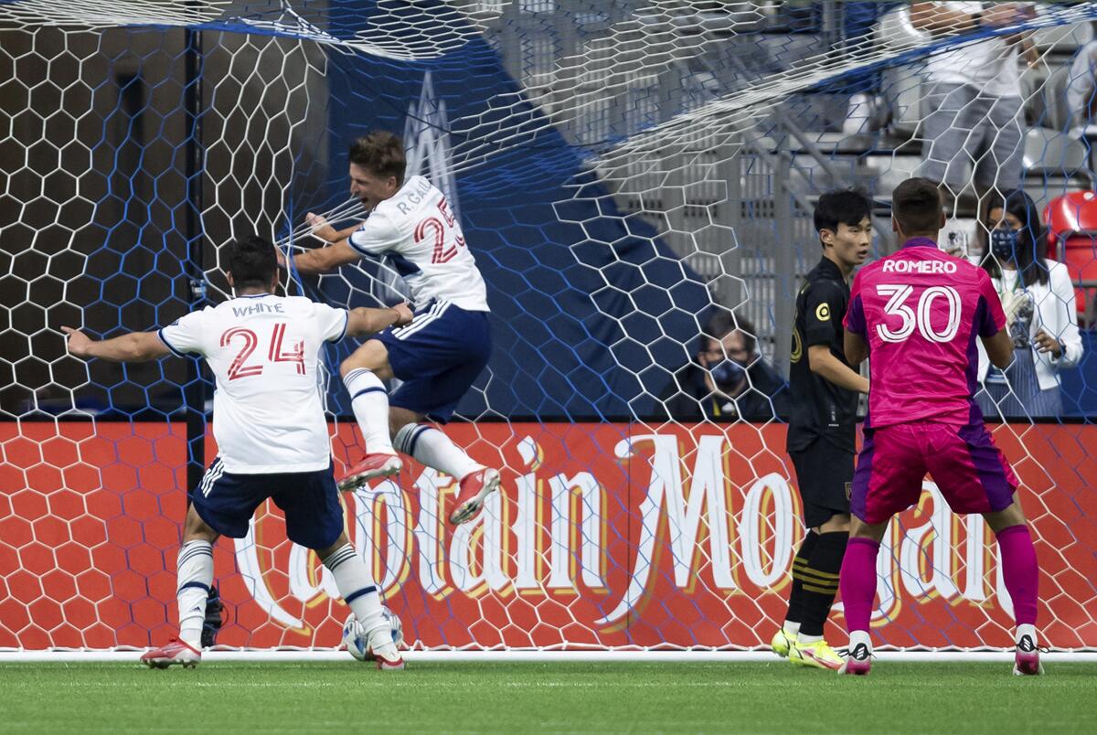 Vancouver Whitecaps' Ryan Gauld jumps into the net and Brian White spreads his arms to celebrate a goal.