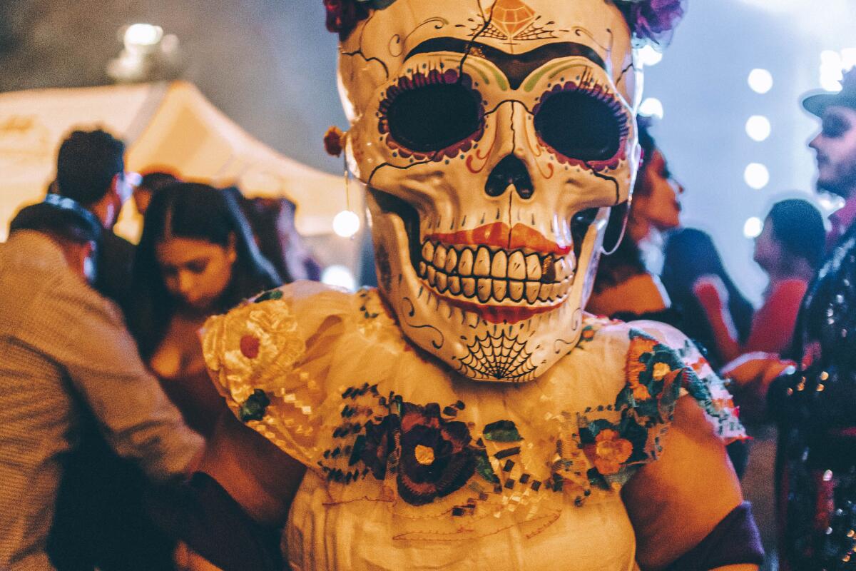 Woman with a Día de Muertos calavera mask on.