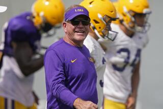 LSU head coach Brian Kelly smiles as he walks across the field during NCAA college football practice.