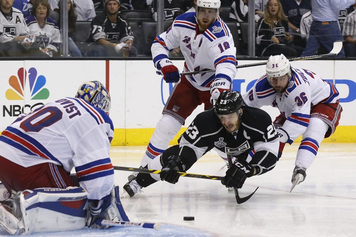 Kings right wing Dustin Brown dives past Rangers defenseman Marc Staal (18) and left winger Mats Zuccarello (36) to attempt a shot against goaltender Henrik Lundqvist in the third period of Game 5 on Friday night at Staples Center.