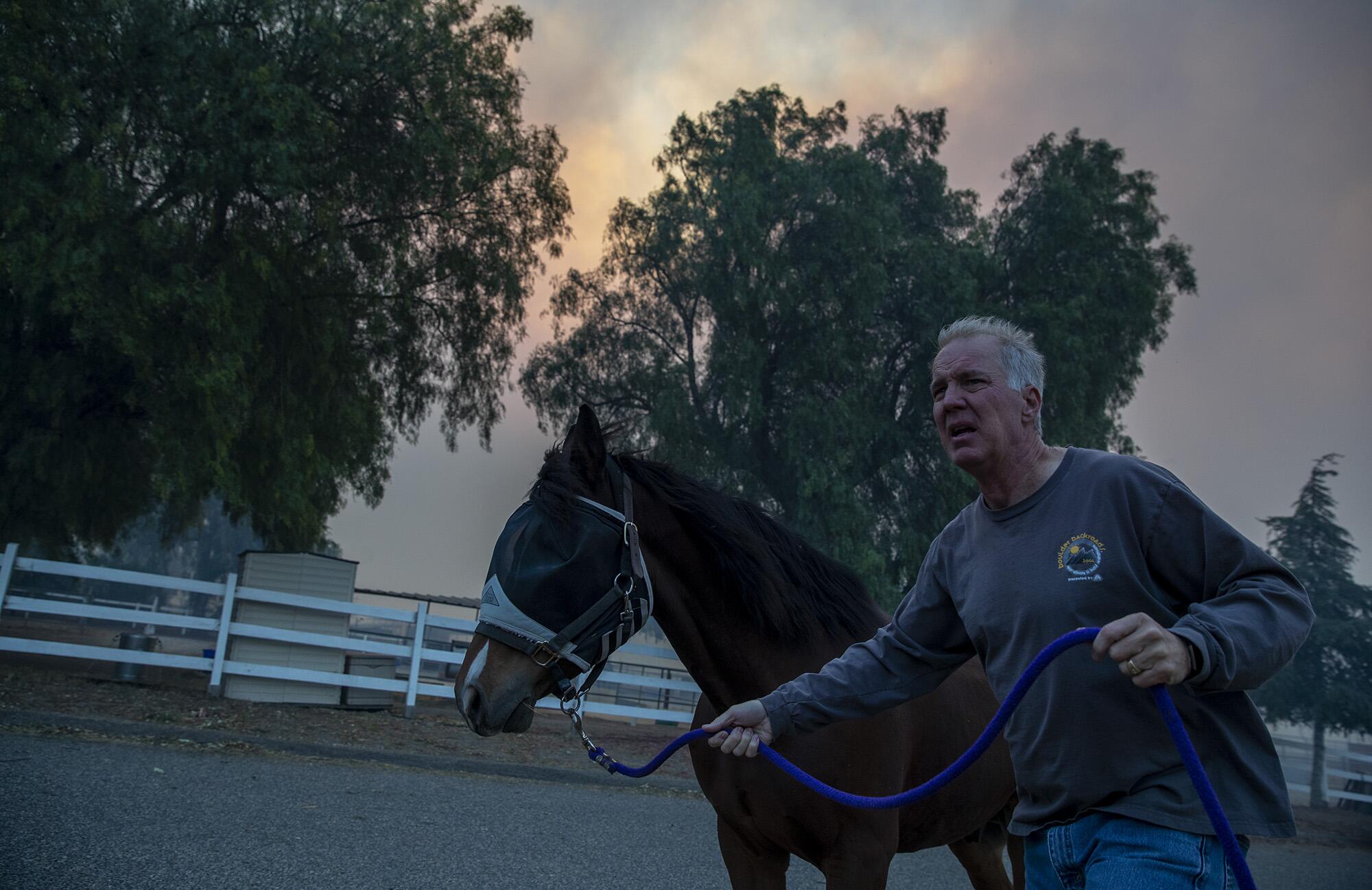 A man flees with a horse as they evacuate Castle Rock Farms while firefighters battle the Easy fire in Simi Valley in 2019.