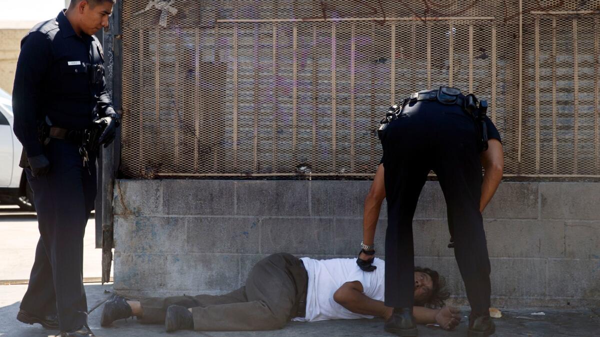 LAPD officers tend to a person who has fallen ill on skid row in August 2016.