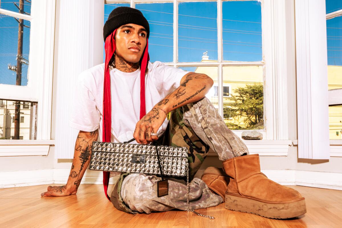 A man with tattoos holds a box with one hand.