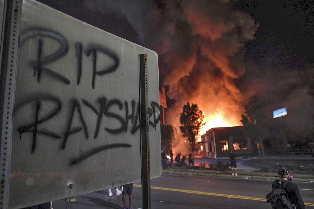 A Wendy's restaurant, background, burns Saturday, June 13, 2020, in Atlanta