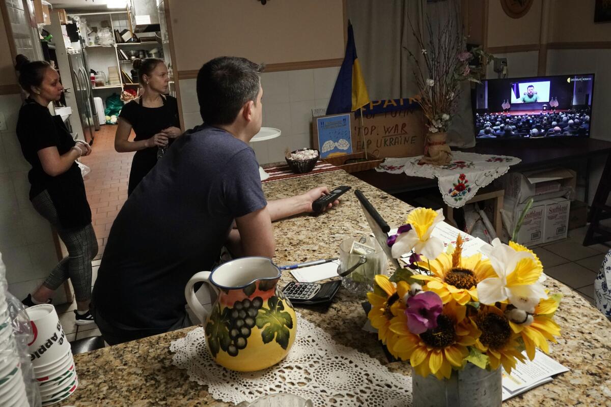 People watch Ukrainian President Volodymyr Zelensky on TV