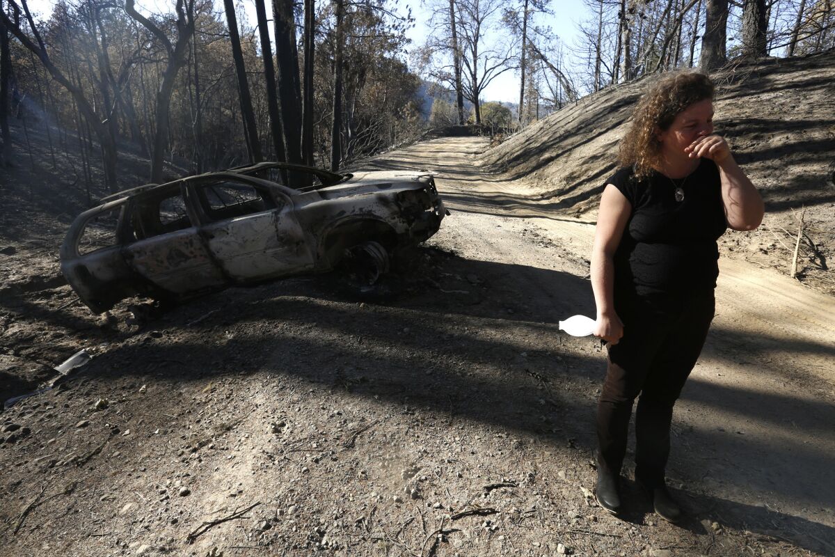 Charlotte Scott stands near her charred Volvo in Redwood Valley.