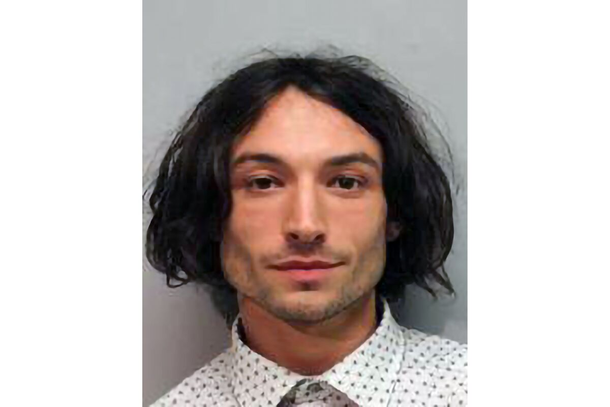 A person with chin-length dark hair and a collared shirt poses for a mug shot