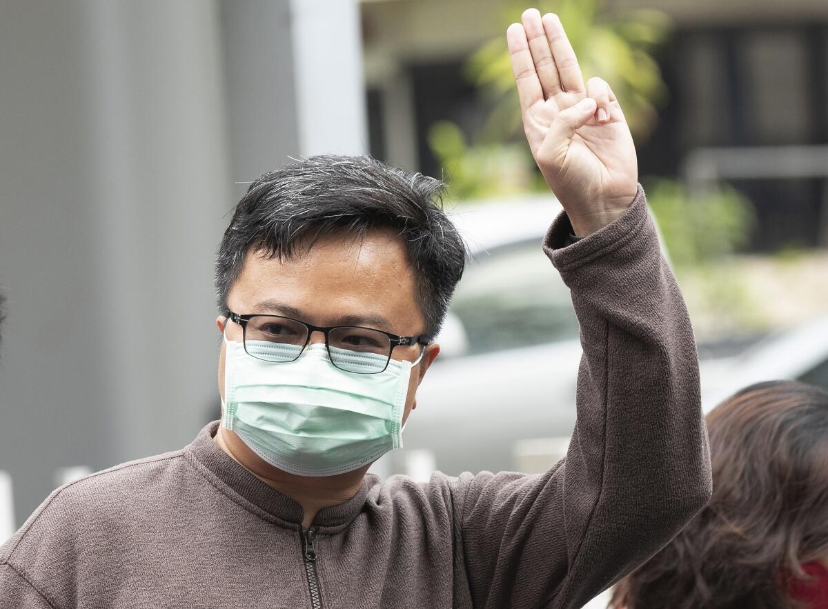 In this Tuesday, Feb. 9, 2021, photo, pro-democracy activist Arnon Nampha raises a three-fingered symbol of resistance at the criminal court in Bangkok, Thailand. A court in Thailand on Tuesday agreed to release Arnon, one of two key leaders of the anti-government protest movement, on bail on the condition that he refrains from activities deemed to defame the monarchy. Arnon must also wear electronic tags and are banned from leaving the country. (AP Photo/Sakchai Lalit)