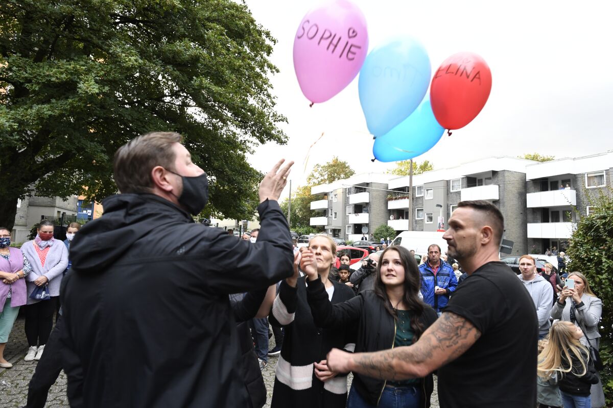Lord Mayor Tim Kurzbach and neighbors hold balloons with the names of the five killed children Saturday in Solingen, Germany.