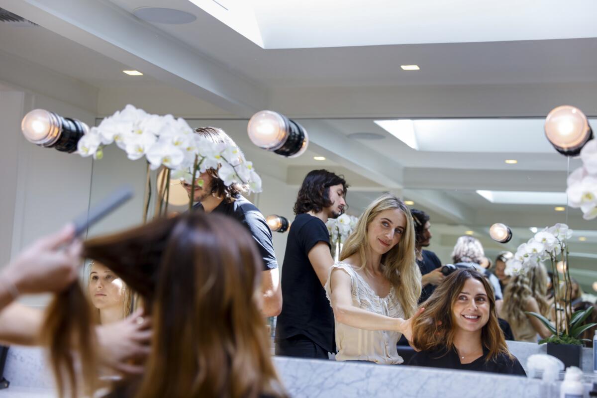 Mara Roszak, second from right, partner and hair stylist at Mare Salon, talks with Ashley Nachum before a quick trim.