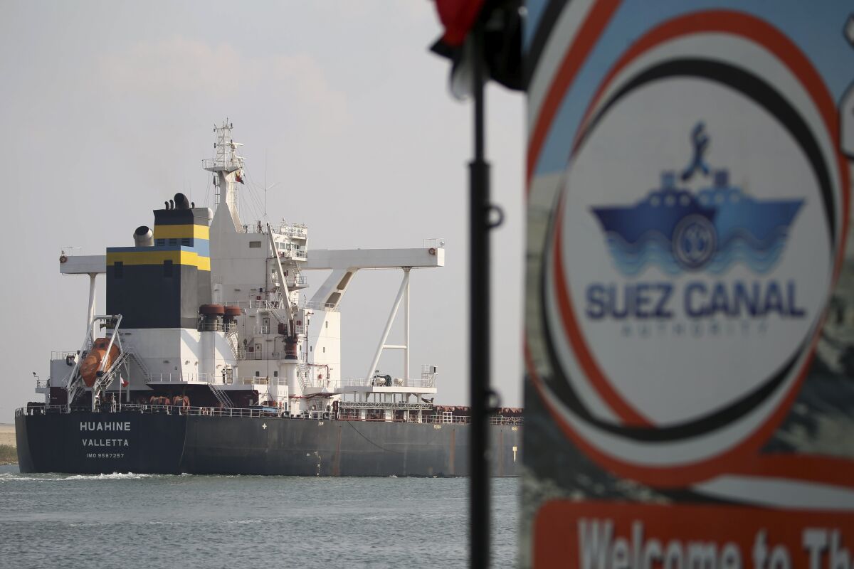 FILE - A cargo ship sails through the town of Ismailia, Egypt, March 30, 2021. Egypt’s Suez Canal said Sunday, May 1, 2022, that its monthly revenues have hit an all-time record, raking in $629 million in April. The unprecedented income came as the Suez Canal in March increased transit fees for ships passing through the waterway. (AP Photo/Ayman Aref, File)