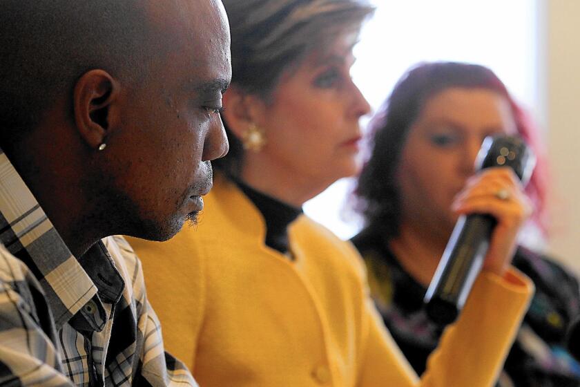 Bret Phillips, left, with attorney Gloria Allred in 2014. Allred holds a flashlight of the same type that Phillips was allegedly beaten with.