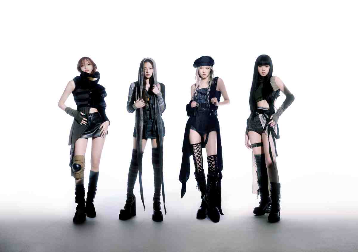 Blackpink's four singers, dressed in black, stand in front of a white backdrop.