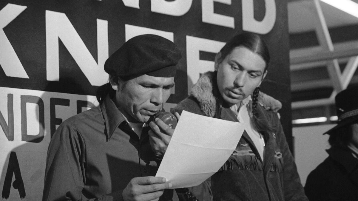 American Indian Movement leader Dennis Banks, left, reads an offer from the U.S. government seeking to end the Native American occupation of Wounded Knee. Looking on is AIM leader Carter Camp.