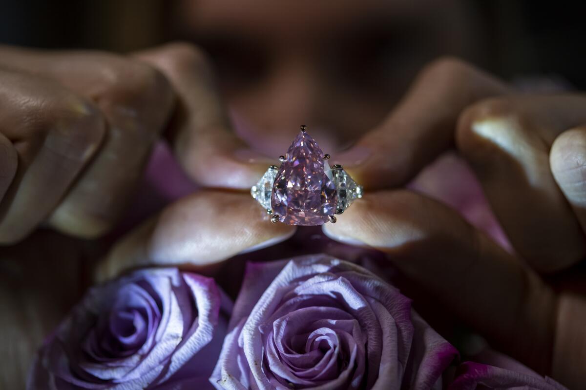 A Christie's employee displays a pink diamond called "The Fortune Pink" of 18,18 carat, during a preview at Christie's, in Geneva, Switzerland, Wednesday, Nov. 2, 2022. The pear-shaped 18-carat pink diamond is set to be sold at auction on Tuesday and is expected to fetch between $25 million and $35 million. (Martial Trezzini/Keystone via AP)