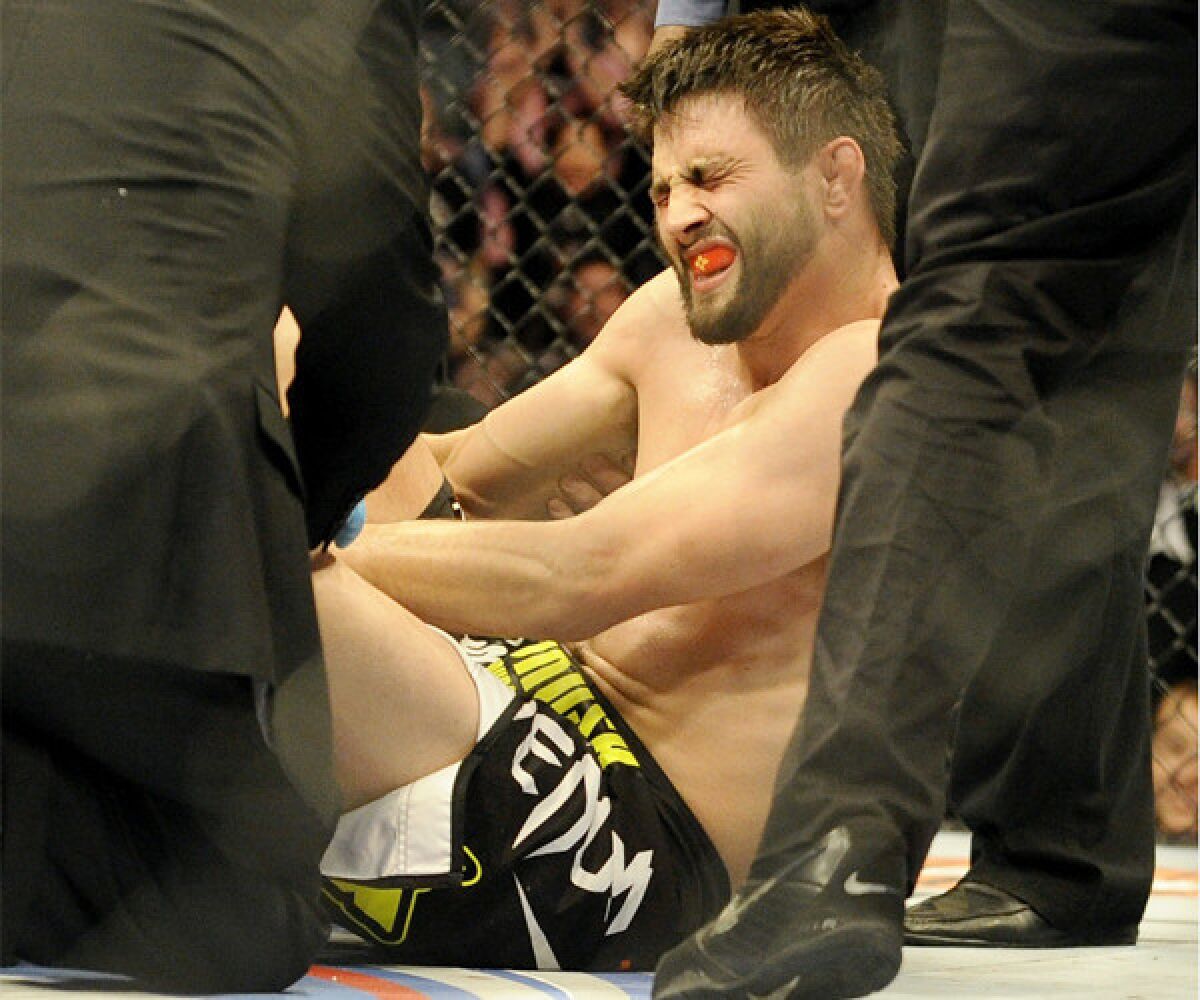 Carlos Condit is tended to by doctors after being injured during his UFC welterweight bout against Tyron Woodley in Dallas on March 15, 2014.
