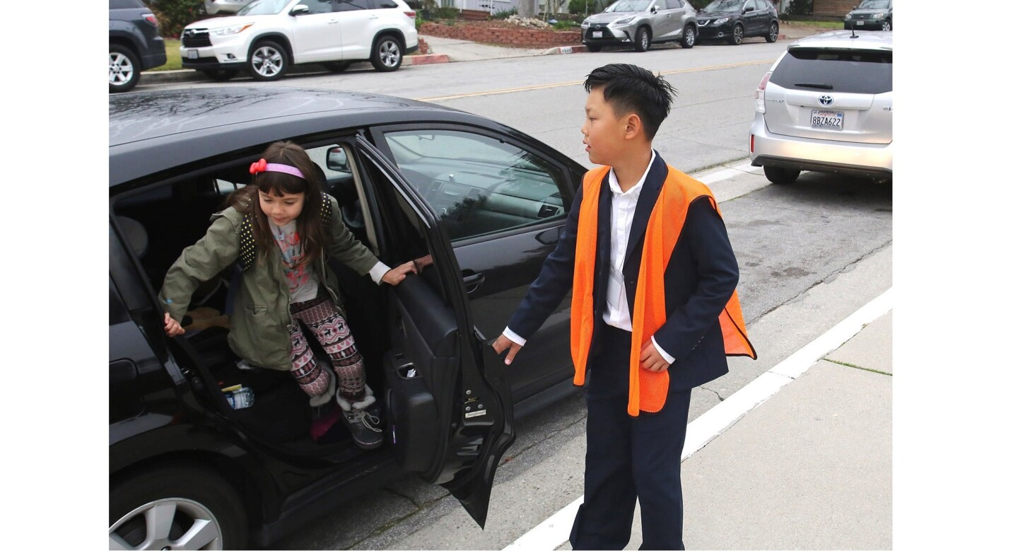 La Cañada Elementary School fifth-grader Ryan Ryu greets his fellow students and opens their car doors at LCE. With help from LCE principal Emily Blaney, Ryan engaged in a full day of administrative activities.