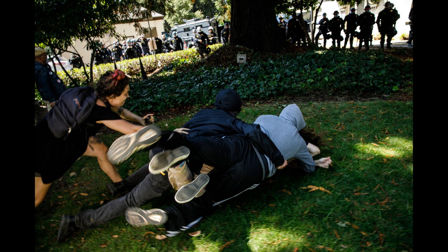 Police watch demonstrators tackle a man Sunday at Martin Luther King Jr. Civic Center Park in Berkel
