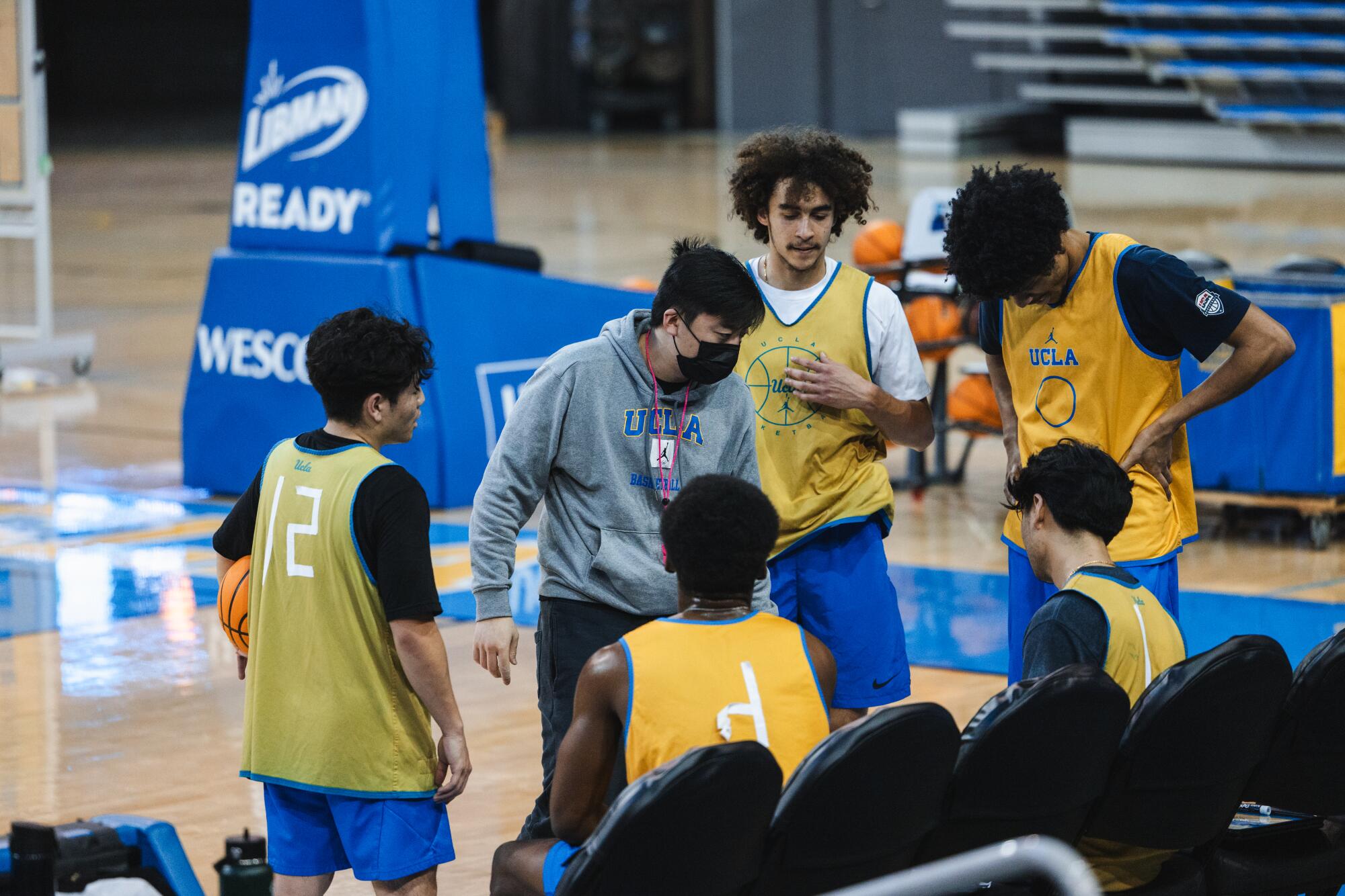 加州大学洛杉矶分校男性球探队球员在女子篮球训练中交谈。 