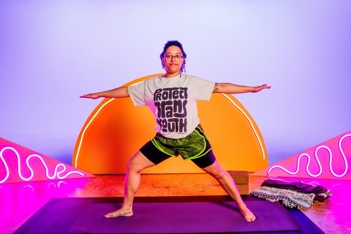 A person in a yoga pose in front of a vibrant orange sun painted on a pink and purple wall