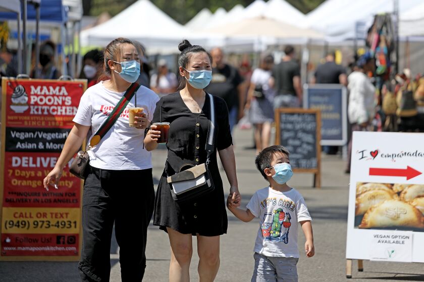 IRVINE, CA - JUNE 15: People make their way down the aisle at the Farmers Market in Irvine Regional Park on Tuesday, June 15, 2021 in Irvine, CA. Restrictions are lifted at most businesses, and Californians fully vaccinated for COVID-19 can go without masks in most settings. (Gary Coronado / Los Angeles Times)