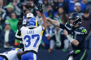 Seattle Seahawks quarterback Sam Darnold passes in front of Rams safety Quentin Lake.