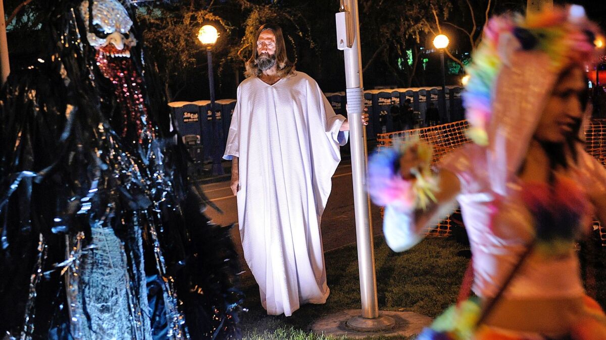 Kevin Short, dressed as Jesus, looks on as people take photos during the Halloween Carnaval in West Hollywood in 2013.