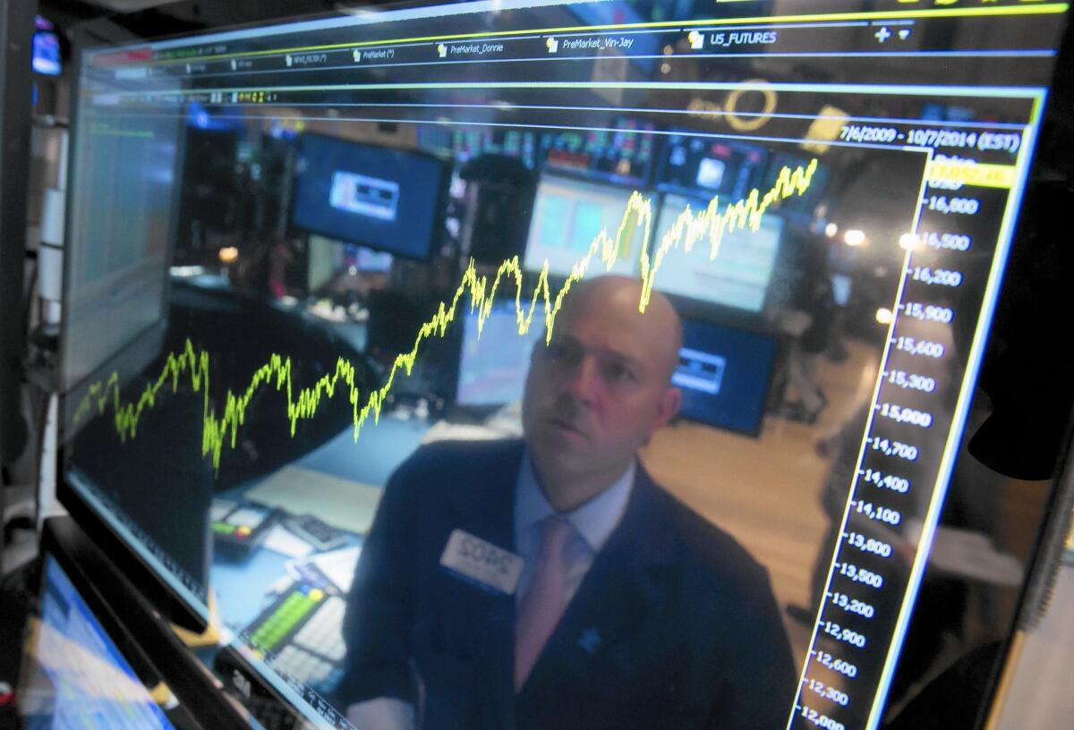 Specialist Jay Woods, working on the floor of the NYSE, is reflected in a screen that shows five years of the Dow index in July 2014.