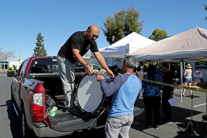 Mariel Teng, left, is helped by Wahid Shorter as he loads his truck with a donated drum in Santa Ana on Saturday.