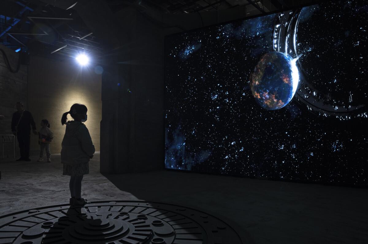 Una niña mira un vídeo que representa el universo de ciencia ficción de una trilogía del autor chino 
