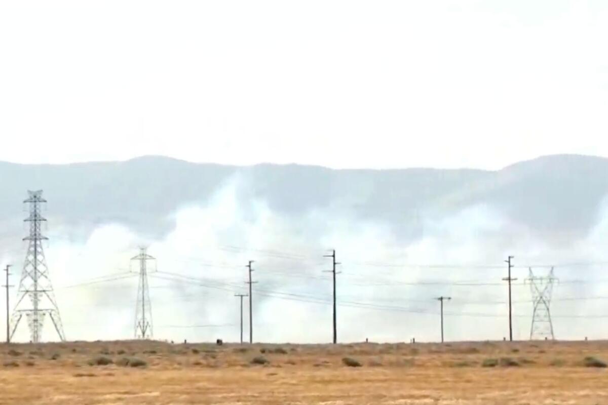 Power lines and clouds of smoke against a backdrop of mountains.