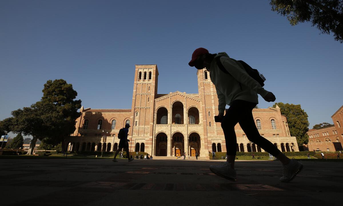 A student walking at UCLA with the Royce Hall building in the background