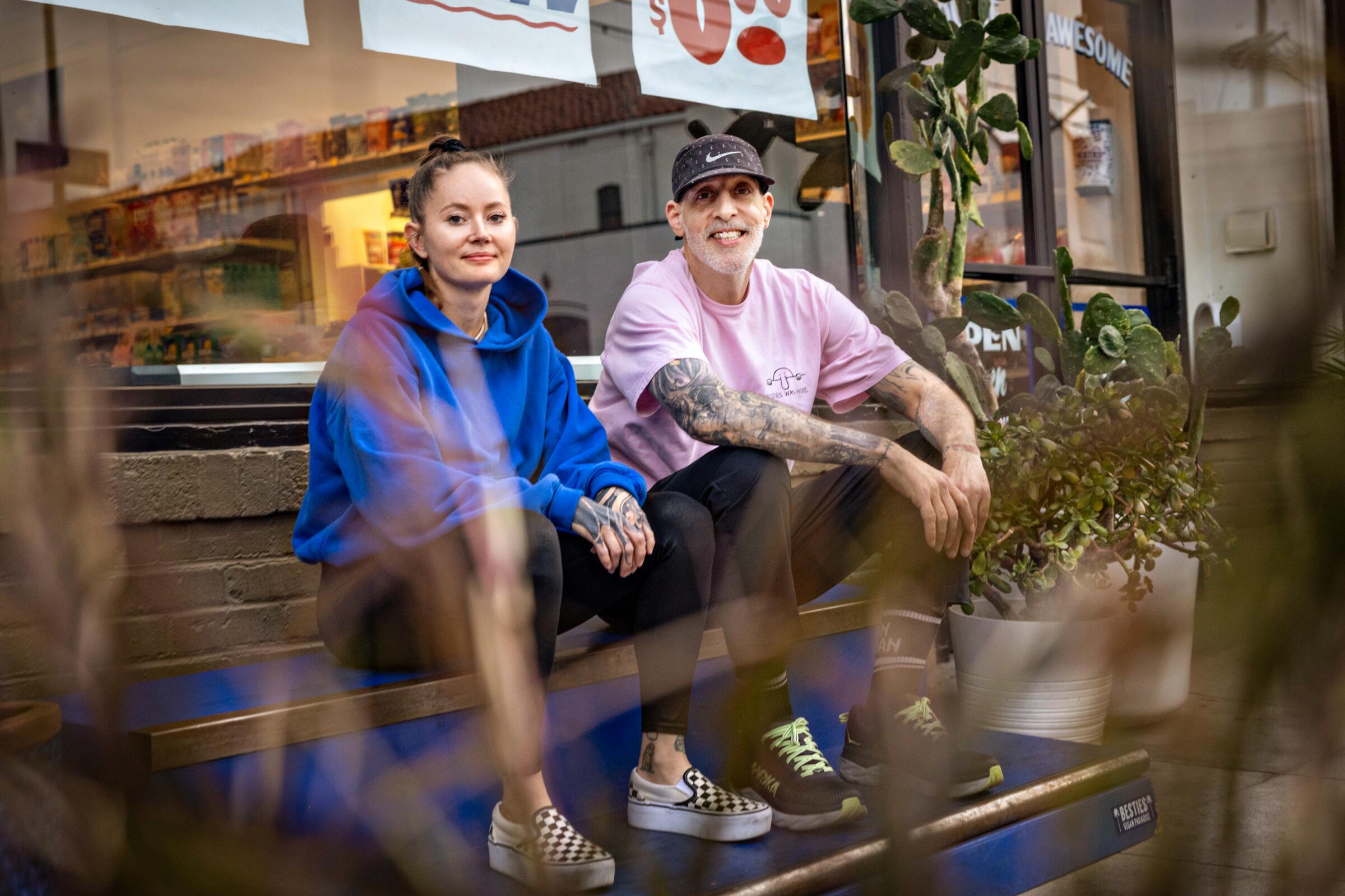 Asia Rain and Matt Fontana sit on the steps outside their store.