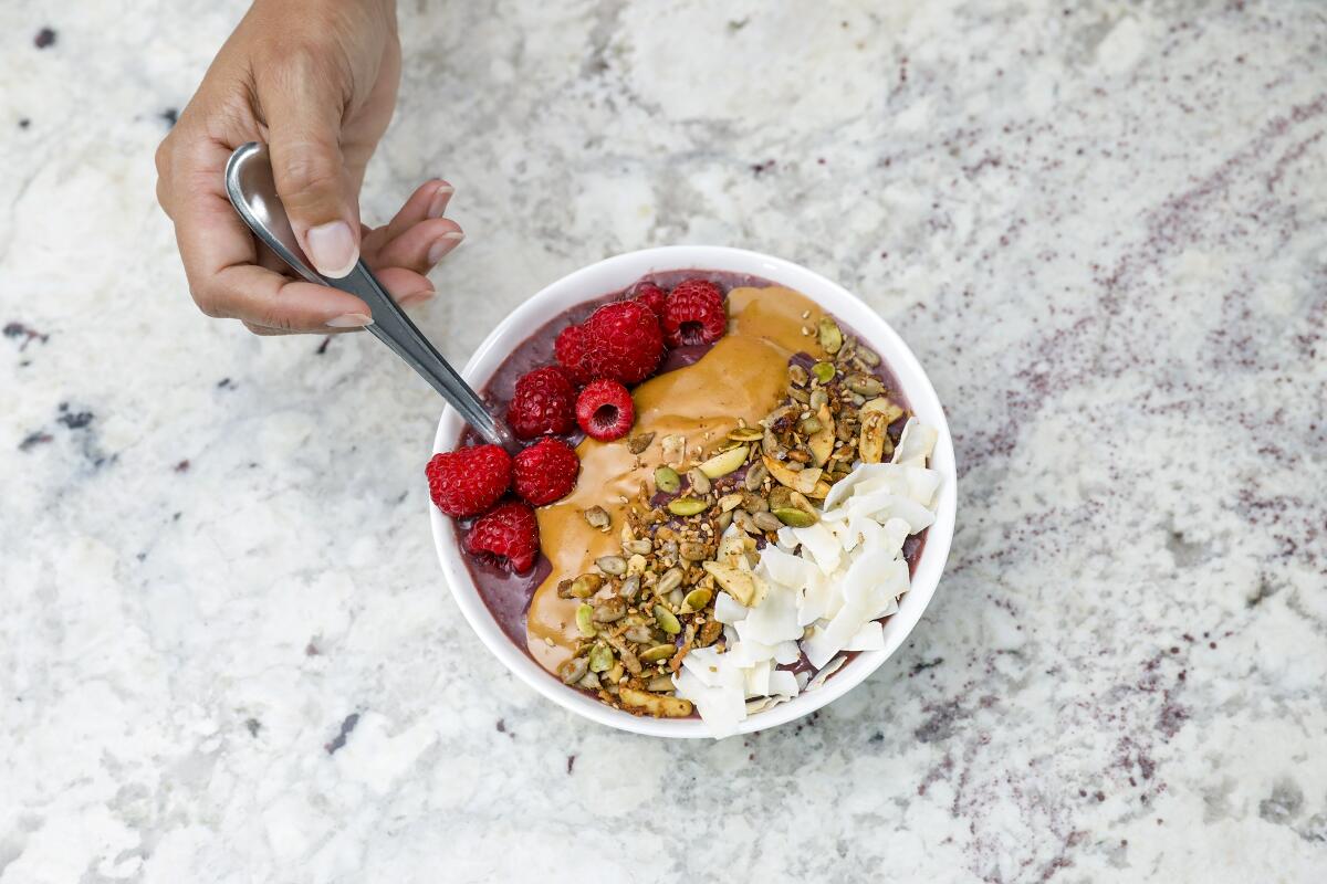 Cynthia Bello makes a raspberry açaí bowl with a thick blend of almond milk, one frozen banana, one açai packet and a cup of frozen raspberries topped with coconut flakes, natural peanut butter, granola and fresh raspberries.