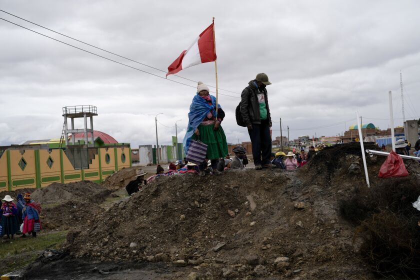 ARCHIVO - Una mujer aymara con una bandera peruana se para sobre un montículo de tierra que sirve de barricada en un camino instalada por manifestantes contra el gobierno en Acora, sur de Perú, 29 de enero de 2023. (AP Foto/Rodrigo Abd, File)